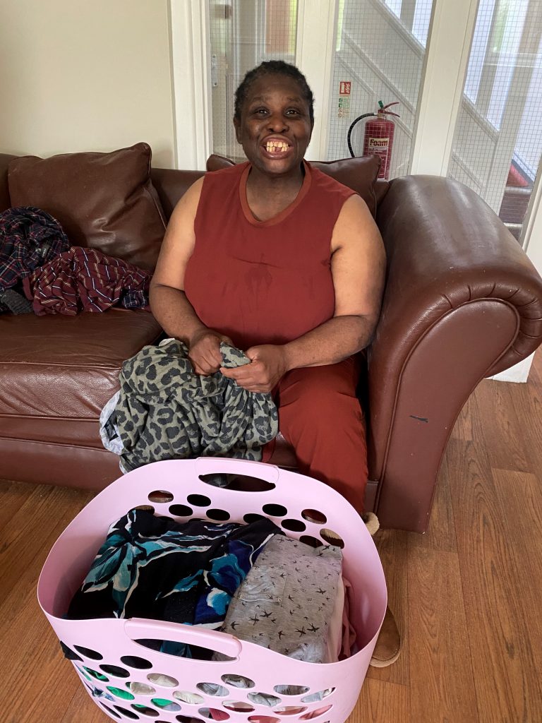 Person we support smiling with a laundry basket