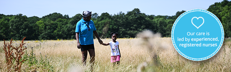 Image of young deaf girl walking hand in hand with a healthcare assistant who is undergoing our complex care training model. They're walking through a field. On the right hand side, there is a blue framed roundal that reads, "our care is led by experienced, registered nurses" with a heart icon.