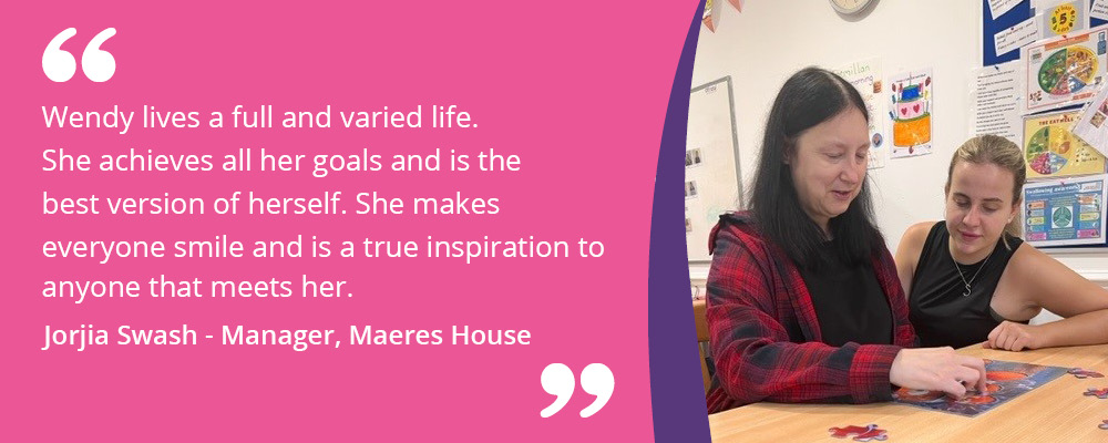 A picture of Wendy with her support worker doing a jigsaw puzzle. A caption reads, "Wendy lives a full and varied life. She achieves all her goals and is the best version of herself. She makes everyone smile and is a true inspiration to anyone that meets her. Jorjia Swash - Manager, Maeres House."